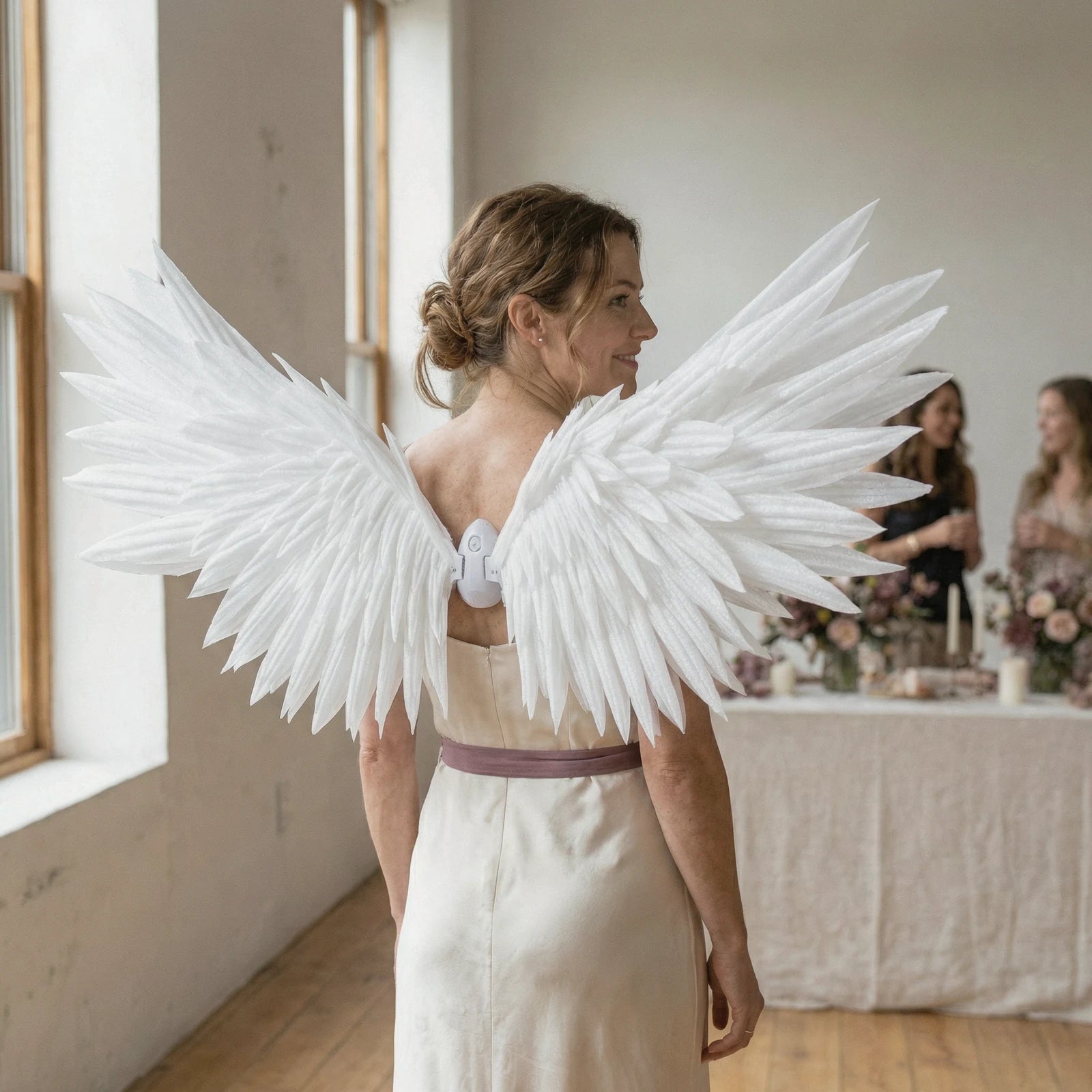 A woman wearing white angel wings at an intimate celebration.